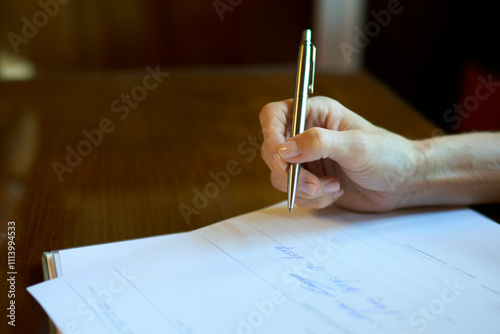 Close-up of a hand signing a document during a wedding ceremony with a gold pen on a wooden table, Dresden, Germany photo