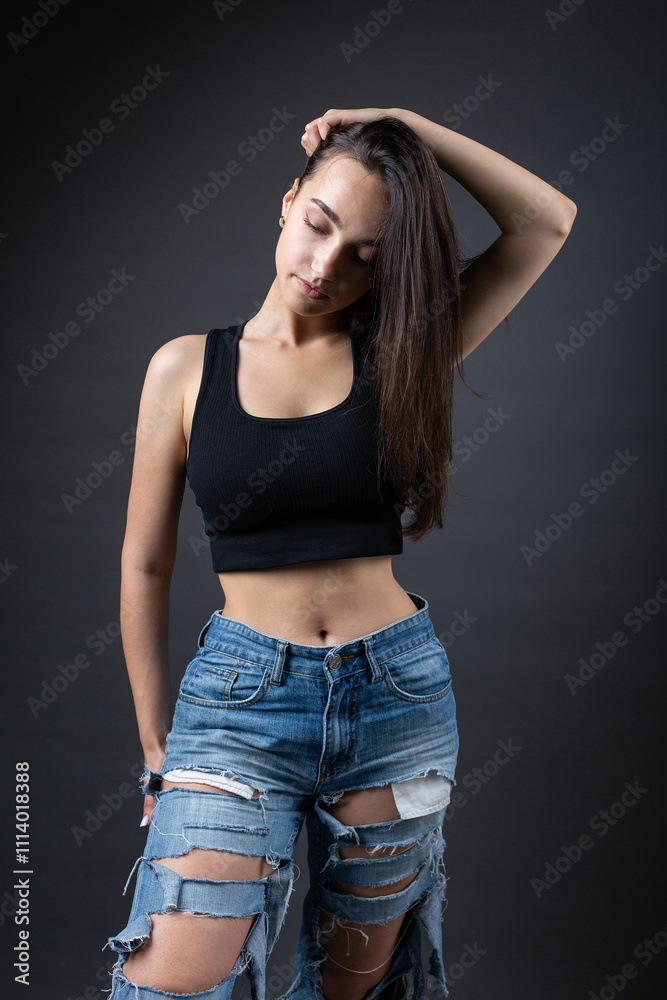 A beautiful brunette poses in the studio wearing a top and jeans. A beautiful brunette poses in the studio wearing a top and jeans.