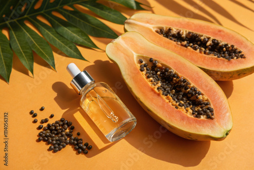 Halved papaya with seeds and a bottle of oil on a vibrant orange surface photo