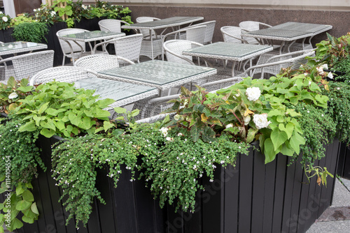 A patio with a lot of plants and a lot of chairs.