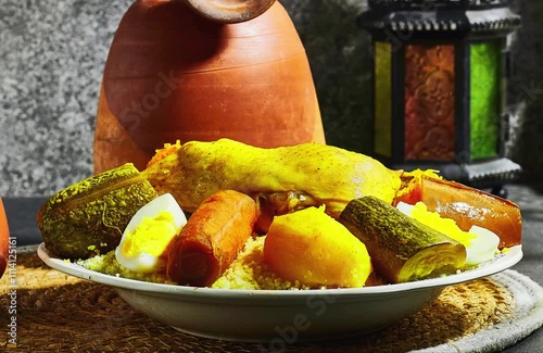 chicken Meat and vegetable couscous in a tajine plate, typical food from Algeria, a traditional festive Arabic dish with herbs and spices and splash milk near window