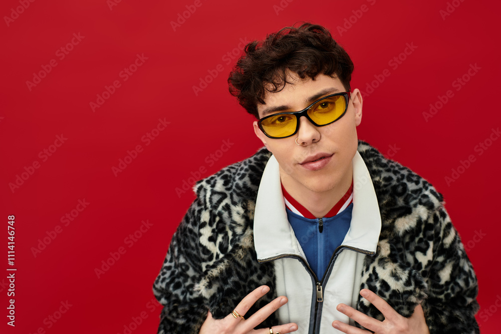 Fototapeta premium Handsome man showcases unique style with yellow glasses and animal print coat in a bold setting.