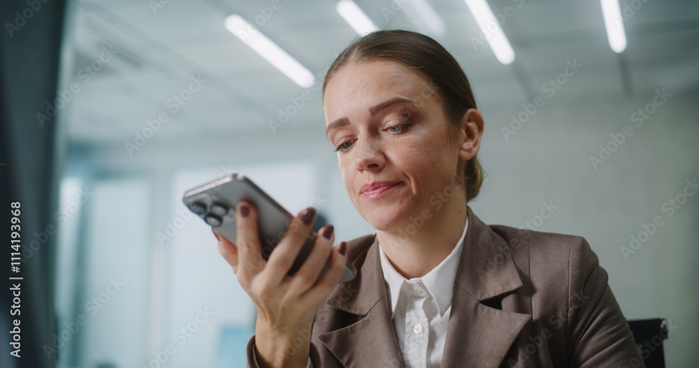 Caucasian woman works in modern office: Female marketing specialist or customer manager sits at workplace, communicates with business partner or client, records voice message on smartphone. E-business Caucasian woman works in modern office: Female marketing specialist or customer manager sits at workplace, communicates with business partner or client, records voice message on smartphone. E-business