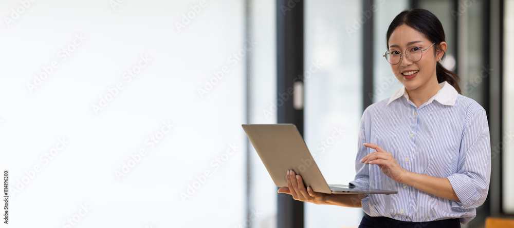 Photo of a business woman wearing glasses Asians stand with smiles and striking eyes. Working with a tablet standing in a room Photo of a business woman wearing glasses Asians stand with smiles and striking eyes. Working with a tablet standing in a room