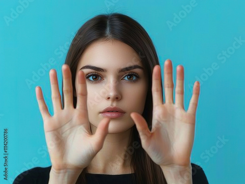 Woman with hands raised against blue background, expressing focus and calm