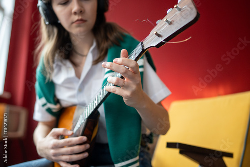 Photography Girl musician plays balalaika in headphones, syncing to melody for training chords and notes
