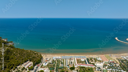 Aerial view of the beach of Peschici bay, in Puglia, Italy, on the coast of the Adriatic Sea. It's a tourist destination in Gargano, in the province of Foggia. There are many beach clubs and umbrellas photo