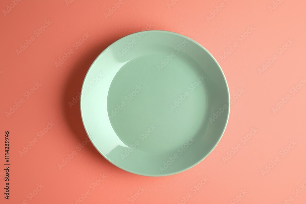 An elegant mint green plate on a soft coral background, showcasing a minimalist and contemporary design. An elegant mint green plate on a soft coral background, showcasing a minimalist and contemporary design.
