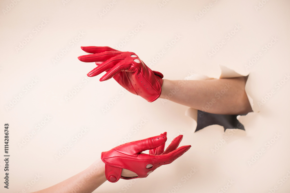 Two tender female hands in leather red gloves on a paper background