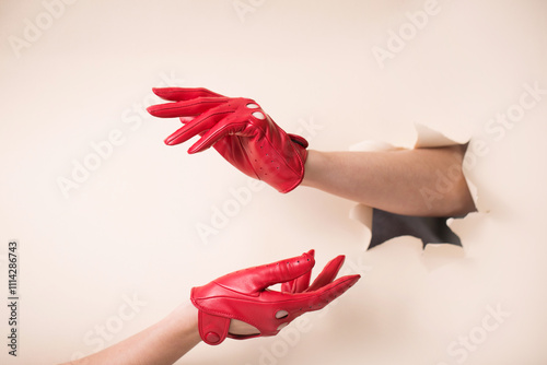 Obraz na płótnie Two tender female hands in leather red gloves on a paper background w salonie