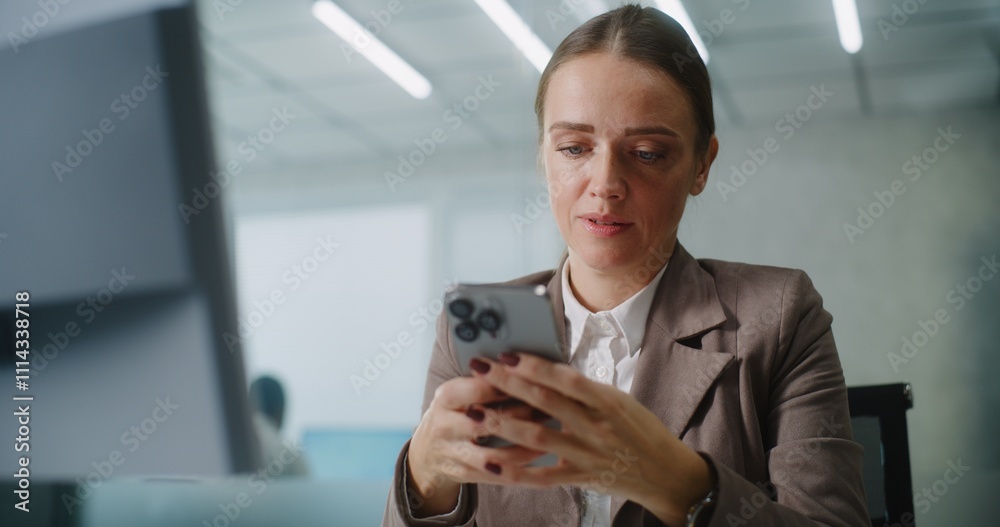 Caucasian businesswoman sits at the workplace, chats with business partner or customer using mobile phone. Female marketing manager or financial specialist works in modern office. E-commerce concept. Caucasian businesswoman sits at the workplace, chats with business partner or customer using mobile phone. Female marketing manager or financial specialist works in modern office. E-commerce concept.