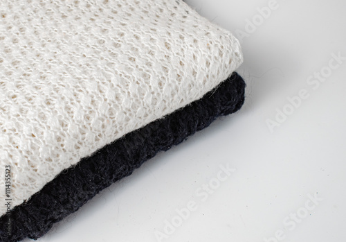 A black and white knitted product are stacked on a white background