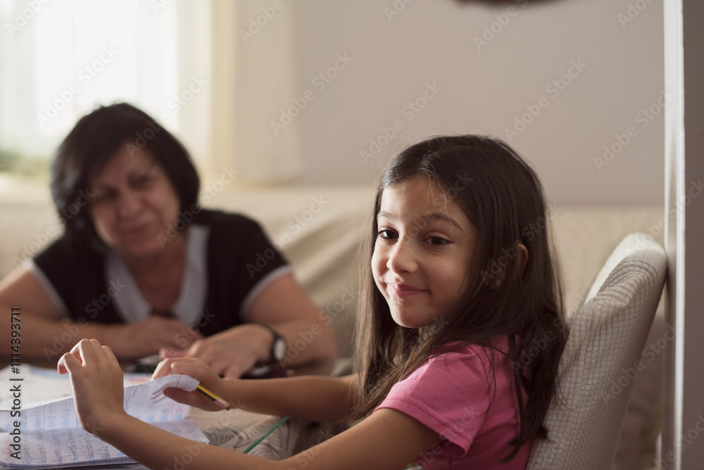Grandmother at home helps granddaughter to do homework Grandmother at home helps granddaughter to do homework