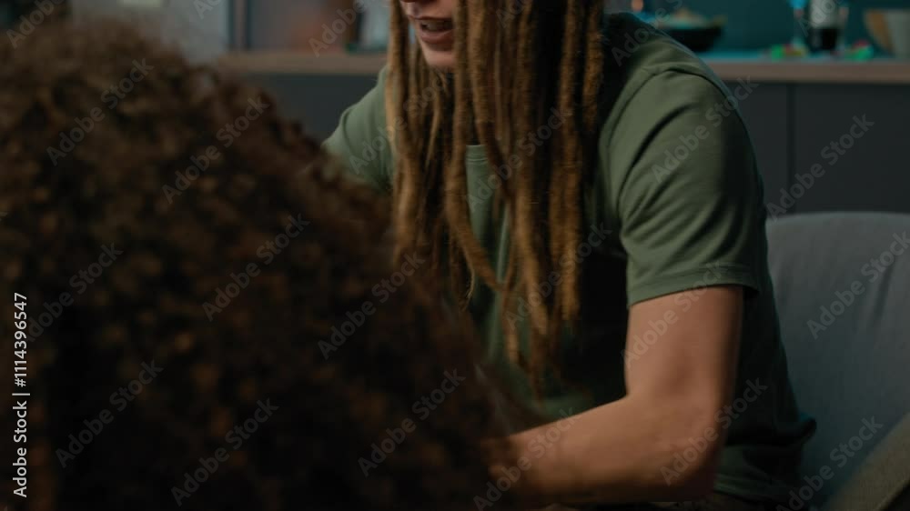 Tilt up slowmo shot of cheerful Caucasian guy with long dreadlocks raising plastic red cup in toast in middle of tabletop gaming process with group of diverse friends in apartment Tilt up slowmo shot of cheerful Caucasian guy with long dreadlocks raising plastic red cup in toast in middle of tabletop gaming process with group of diverse friends in apartment