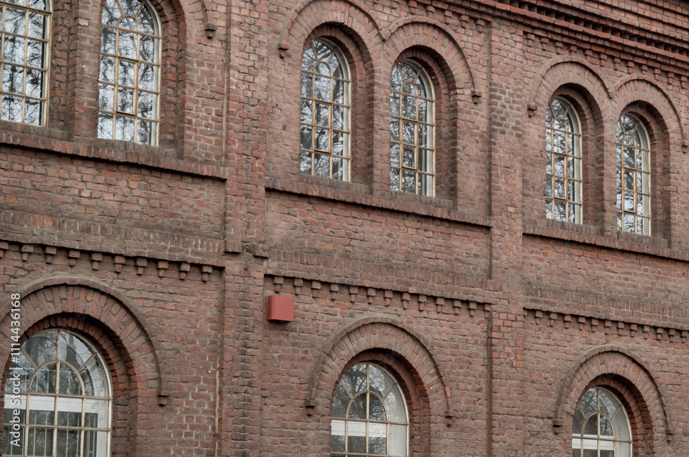 Obraz premium Arched windows illuminating red brick industrial building facade