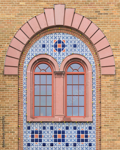 Two decorative windows surrounded by mosaic tiles under arch