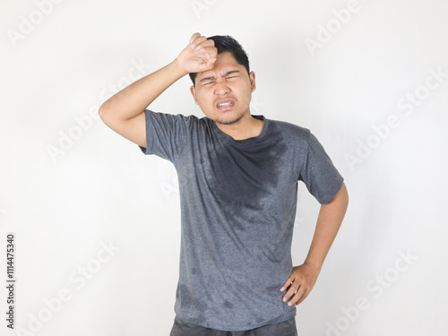 Asian man sweating while wiping sweat from his forehead with a face that looks uncomfortable