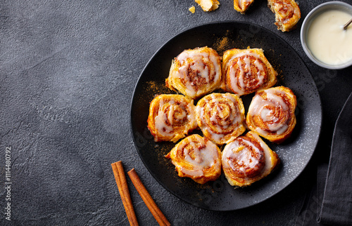 Cinnamon rolls, buns, cinnabons on black plate. Dark background. Close up. Copy space. photo