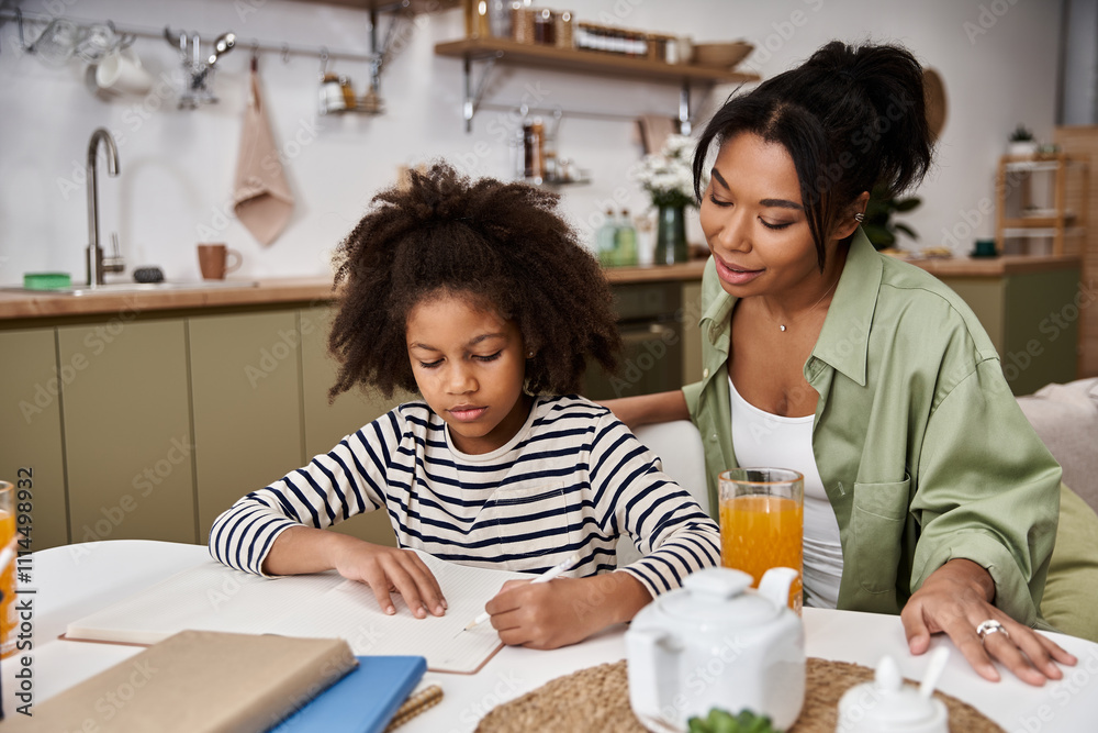 A mother helps her daughter draw at a bright kitchen table, enjoying a cozy afternoon. A mother helps her daughter draw at a bright kitchen table, enjoying a cozy afternoon.