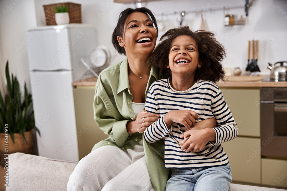 A mother and her daughter are laughing together in a bright kitchen, sharing a loving moment. A mother and her daughter are laughing together in a bright kitchen, sharing a loving moment.