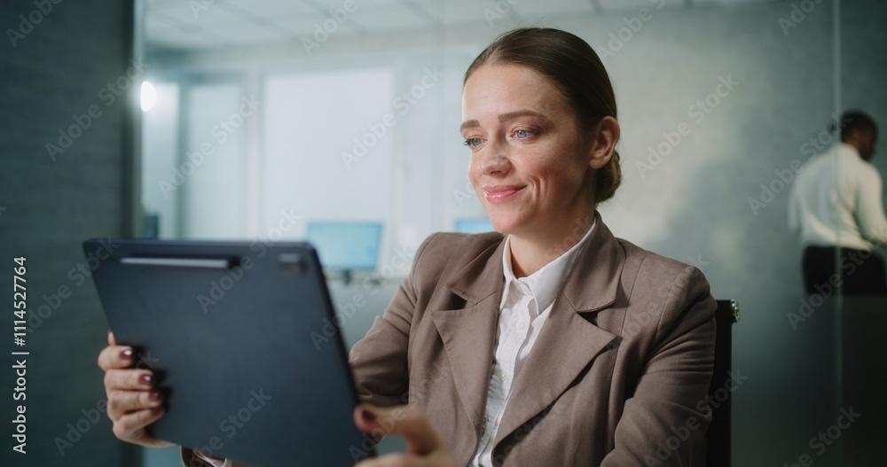 Caucasian woman works in modern office: Female marketing specialist or customer manager sits at the workplace, chats with business partner or client on video conference on tablet computer. E-business. Caucasian woman works in modern office: Female marketing specialist or customer manager sits at the workplace, chats with business partner or client on video conference on tablet computer. E-business.