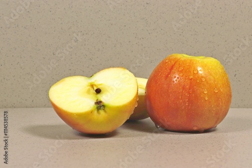 A whole apple and an apple cut in half.