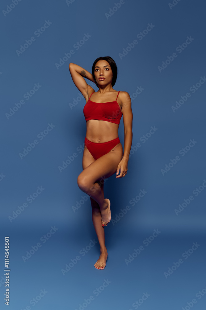 Fototapeta premium A stunning young Black woman with brunette hair exudes fashion and confidence in a studio.