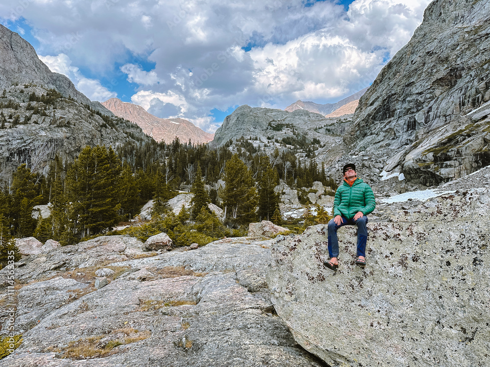 A young man sits on a rock in the Wind River Range of Wyoming. A young man sits on a rock in the Wind River Range of Wyoming.