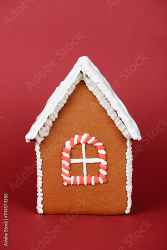 The hand-made eatable gingerbread house and snow decoration on red background