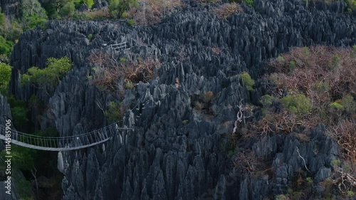 Female tourist is making her way across a hanging bridge in the Tsingy de Bemaraha National Park, a UNESCO World Heritage Site
