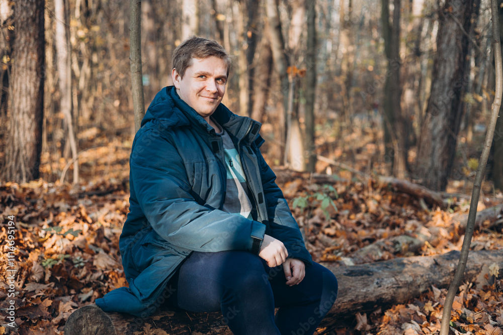 30s Plus size male smiling outside on an adventure. Hiking, lifestyle, adventure and tourism concept. Young man standing in woodland and looking at the camera, autumn time