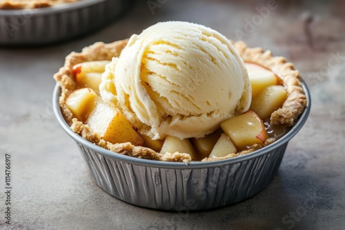 A single scoop of apple pie ice cream, with chunks of pie crust and apple, in a small pie tin. photo