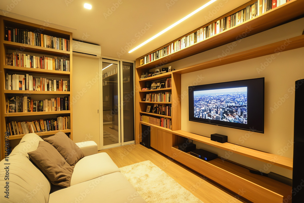 Fototapeta premium A cozy room with built-in bookshelves, a TV, and a couch