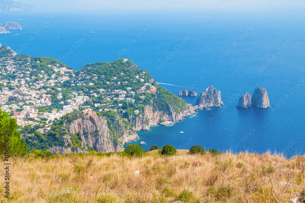 view of Capri, including the Gardens of Augustus, with vibrant flowers, lush greenery, and panoramic vistas of the coastline and iconic Faraglioni rocks.