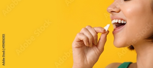 Fotografie Young woman with chewing gum on yellow background with space for text, closeup