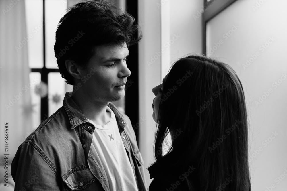Fototapeta premium Young couple sharing an intimate moment indoors in soft natural light
