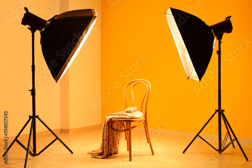 Modern photo studio with chair, plaid and professional lightening equipment photo