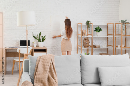 Young woman hanging paintin...