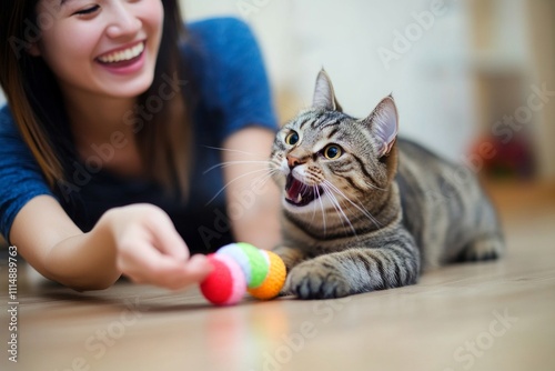 Asian female adult enjoying playtime with cat and colorful toys indoors photo