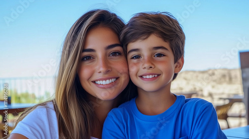 Joyful mother and son smiling together outdoors with blue sky