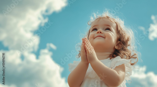 Little girl praying with hands clasped under a cloudy blue sky