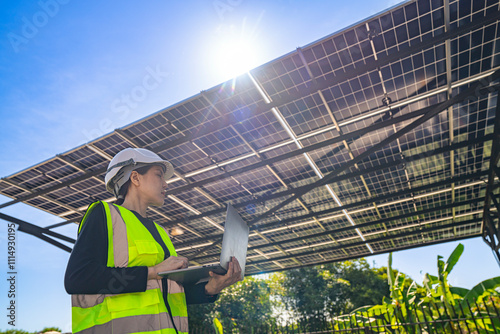 ngineer inspecting solar panel installation on a modern structure, pointing to details while holding a laptop, highlighting sustainable energy solutions, efficient design, and renewable innovation. photo