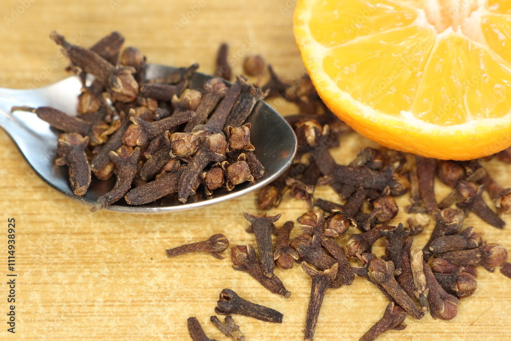 Fototapeta premium A visually appealing arrangement of cloves and an orange slice displayed on a rustic wooden surface