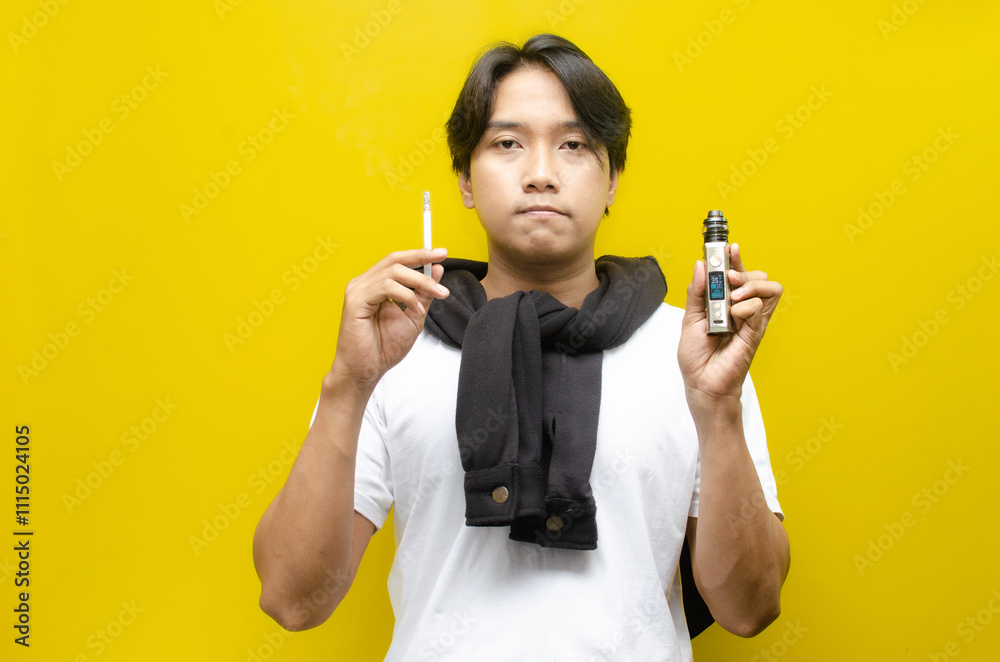 Fototapeta premium Cigarette vs E-Cigarette Concept. Young Asian Man Smoking and Vaping with Thick Smoke.