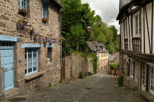 View of the medieval street of the city with half-timbered houses descending to the embankment of the Rance River on a sunny summer day, Dinan, Cotes-d'Armor, Brittany, France