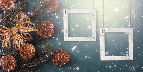 Christmas background with two empty picture frames mockup, decorative fir tree branch, bow and cones for decoration. New Year winter holidays concept with decor and copy space, snowy top view banner.