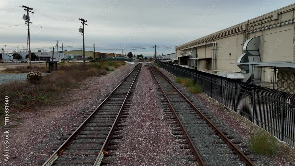 Old railway with grass and Iron fences and electricity poles in the morning with a cloudy sky Old railway with grass and Iron fences and electricity poles in the morning with a cloudy sky