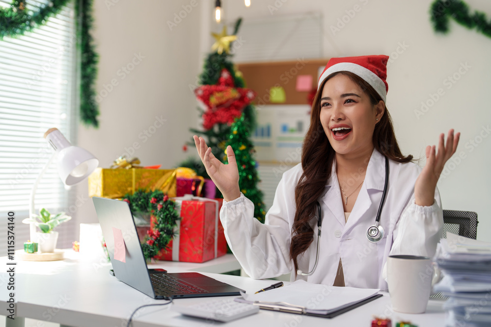 Doctor working at desk on Christmas Eve wearing a festive Santa hat She uses a laptop to communicate with work. Have fun chatting online happy surprised Excited during the holiday season. Doctor working at desk on Christmas Eve wearing a festive Santa hat She uses a laptop to communicate with work. Have fun chatting online happy surprised Excited during the holiday season.