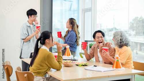 Photography Smiling diverse Asian employees enjoy drinks and conversations while celebrating at an office party