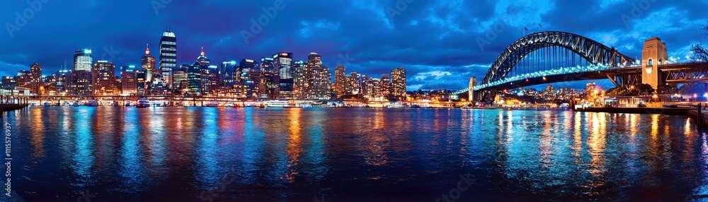 Fototapeta premium Stunning Night View of Sydney Cityscape with Harbor Bridge and Reflections in Water at Dusk